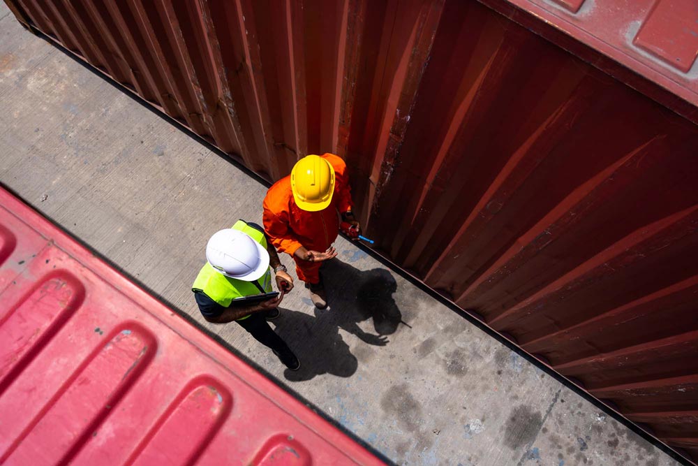 Två kollegor som går bredvid två containers